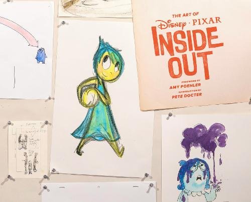“The Art of Inside Out” book cover and character sketches pinned to a wall.
