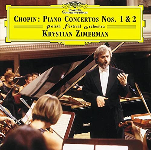 Krystian Zimerman conducting an orchestra with a grand piano in a concert hall.