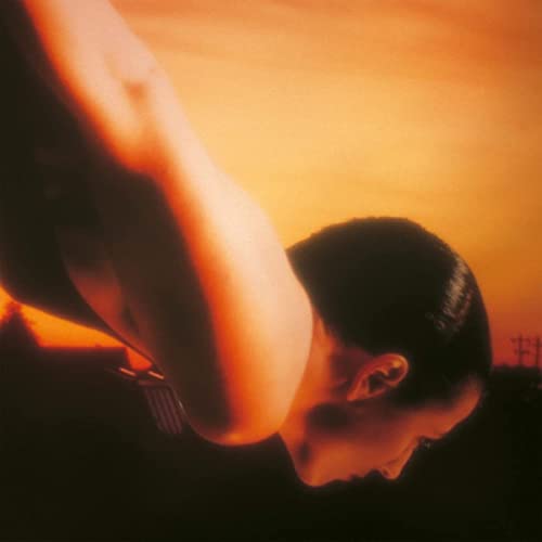 Close-up of a person with head bowed against an orange sunset.