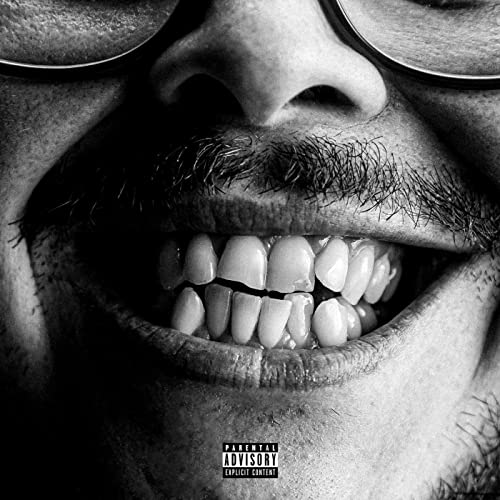 Black and white close-up of a smiling man wearing glasses with parental advisory label.