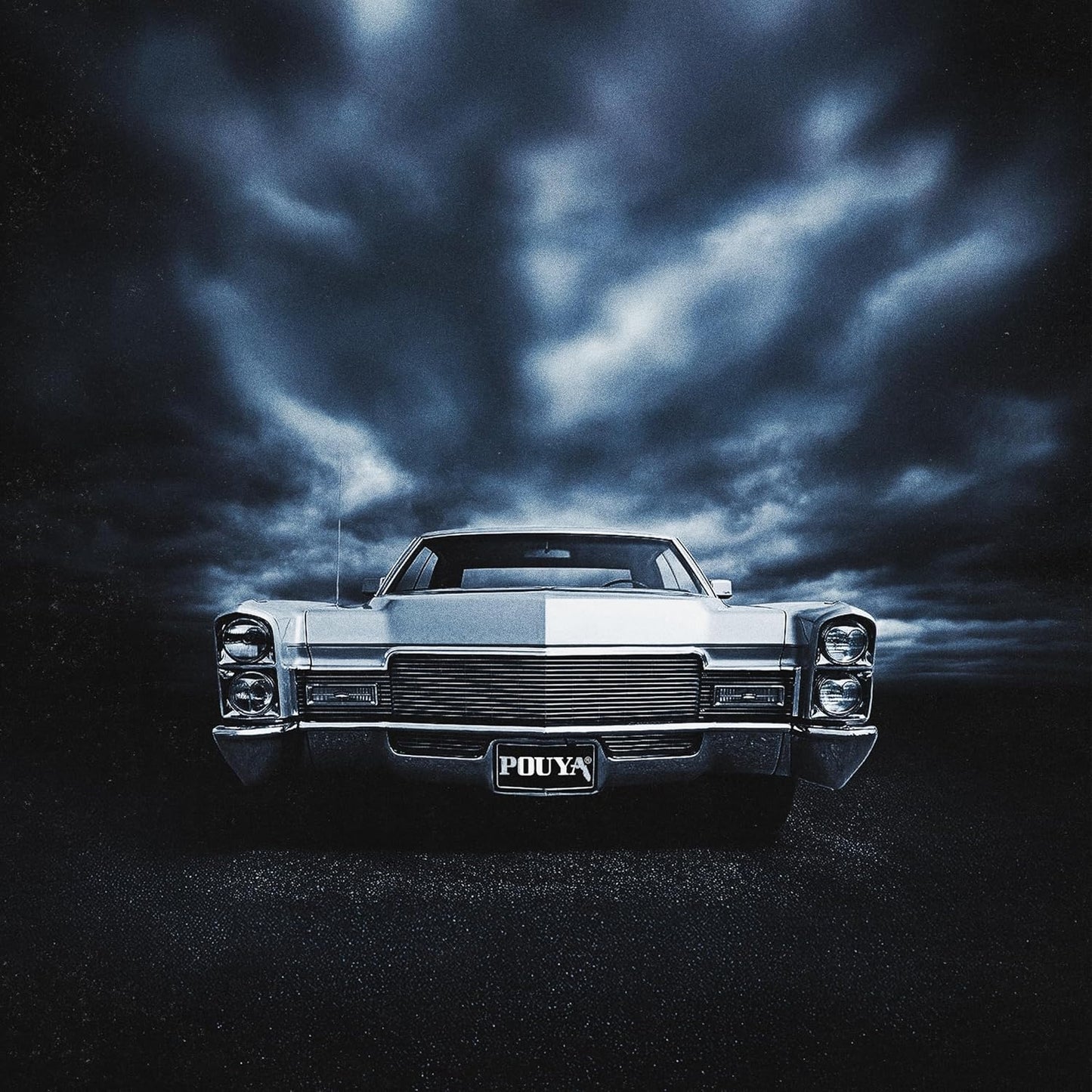 Front view of a vintage car under a dark, cloudy, monochromatic blue sky.