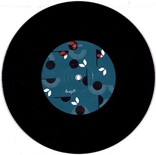 A black seven-inch vinyl record with a teal label featuring abstract white and red patterns.