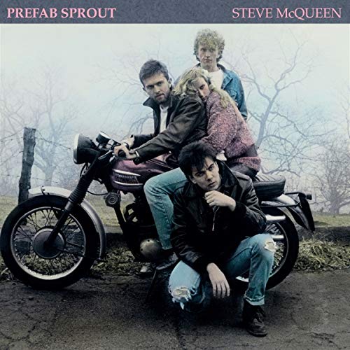 Four band members pose with a motorcycle in a misty, rural landscape.