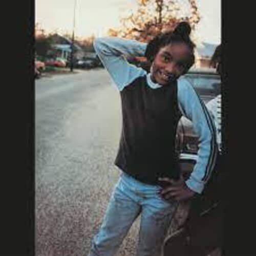 Young woman smiling and stretching outdoors, with cars in the background.