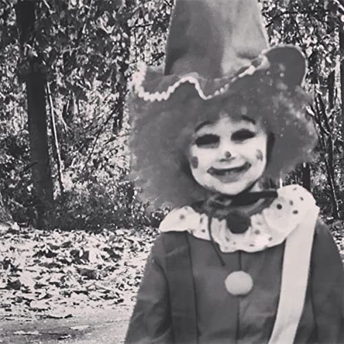 Black and white photo of a child in unsettling clown attire.