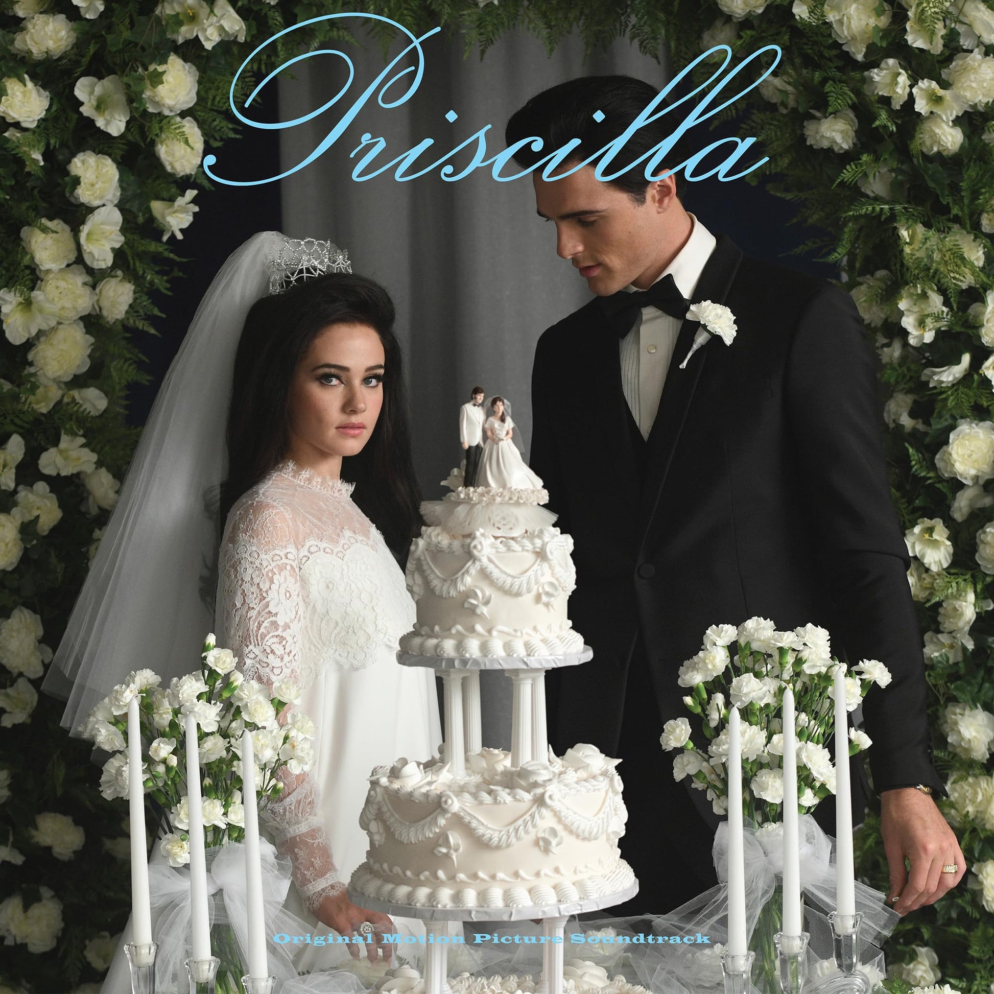 Wedding photo of a bride and groom in front of a floral backdrop.
