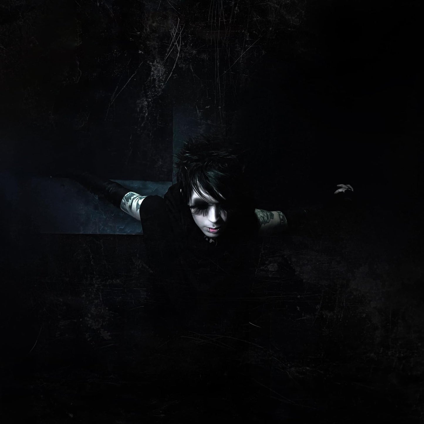 Dark portrait of a person with pale skin and dark hair, looking at the viewer.