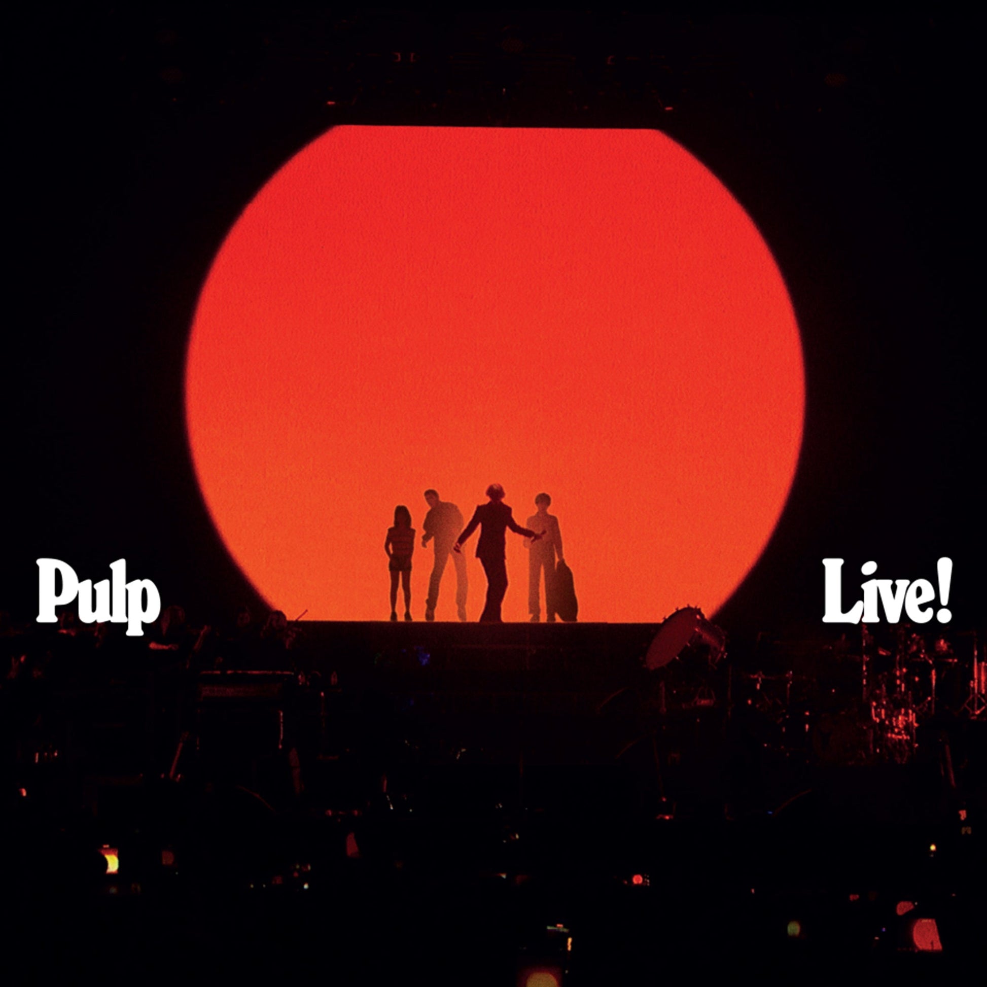 Silhouetted band Pulp performing on stage before a large red circle.