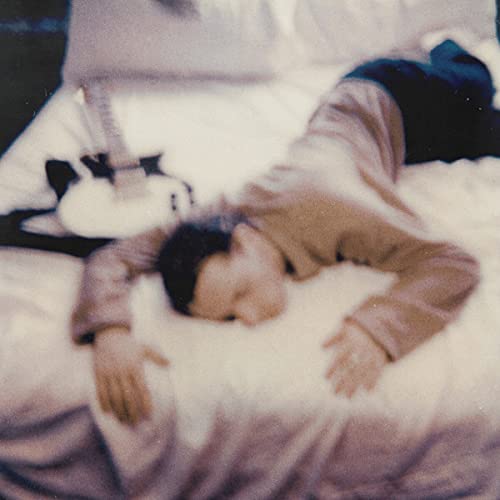 Close-up of a person lying on white bedding, muted tones.