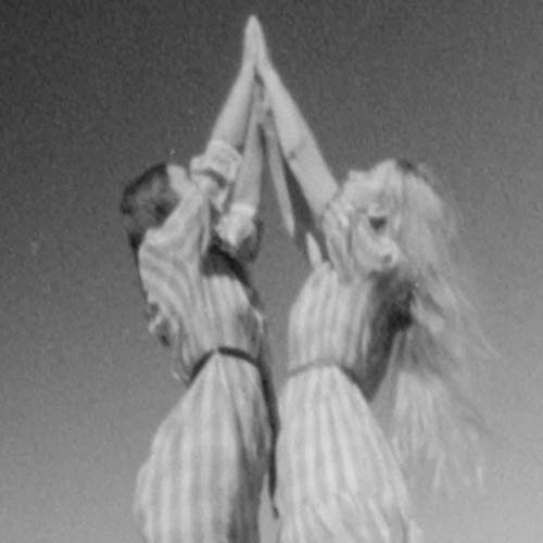 Two figures with raised arms in a blurred, grayscale photograph.