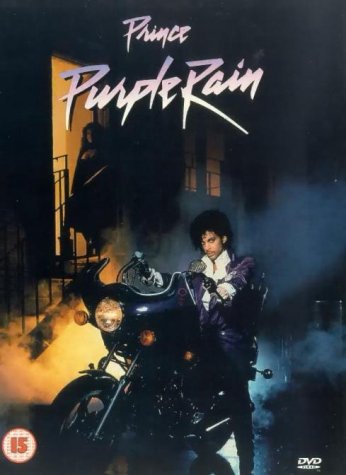 Prince sits on a motorcycle in front of a building in the Purple Rain DVD.