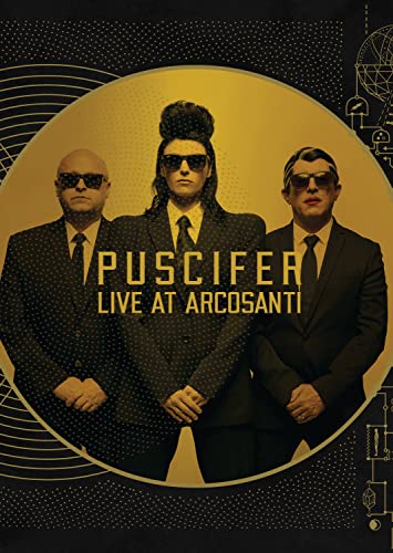 Puscifer band members in suits and sunglasses, golden circular background.