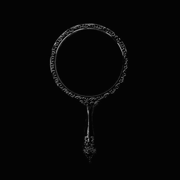 Ornate, black hand mirror against a solid black background.