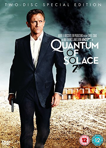 Daniel Craig in a suit holding a gun with a burning building in background.