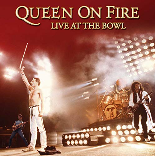 Queen performing live on stage with bright lights and smoke effects.