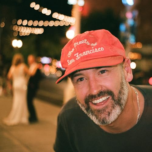 Man wearing a red "San Francisco" cap, smiling at the camera.