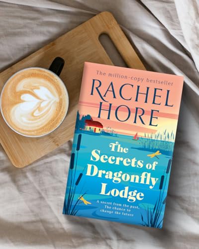 Book cover with a lakeside scene, coffee cup, and wooden board.