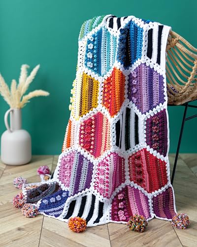 Colorful crocheted hexagon blanket draped on a wicker chair, with yarn balls.