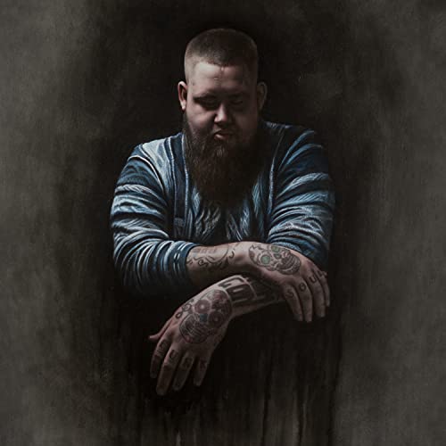 Rag'n'bone Man portrait with tattoos, against a dark, textured background.
