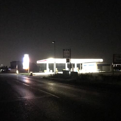 Dark, blurry image of a brightly lit gas station at night.
