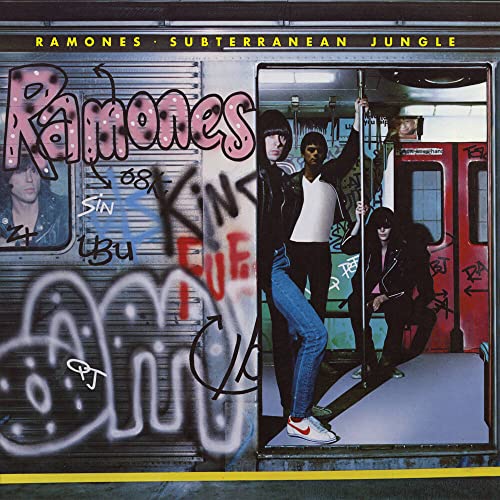The Ramones stand inside a graffiti-covered New York City subway car.