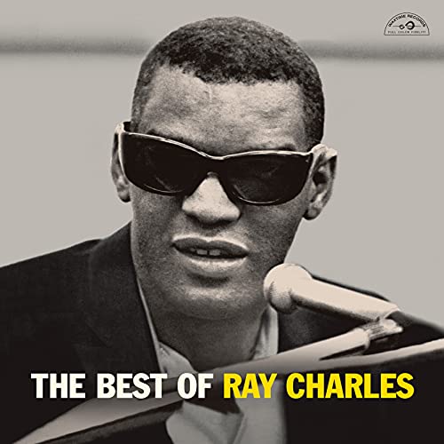 Black and white portrait of Ray Charles wearing sunglasses with a microphone in front.