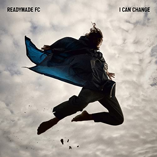 A person in a dark poncho leaps against a cloudy sky on this album cover.