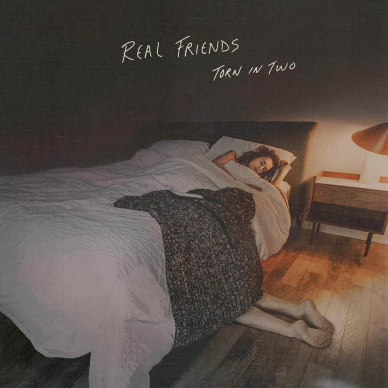 A person lies in bed with their legs extending out from under the covers.