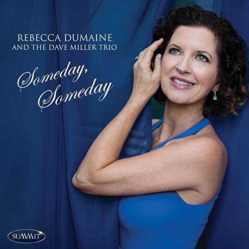 Rebecca Dumaine poses in a blue top against a blue curtain for her album cover.