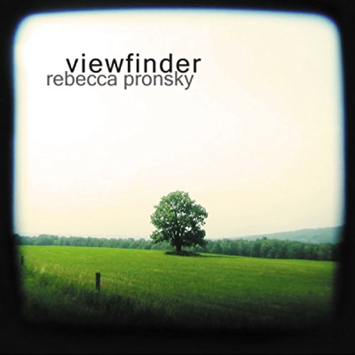 "Album cover with a tree in a green field, viewed through a camera viewfinder."
