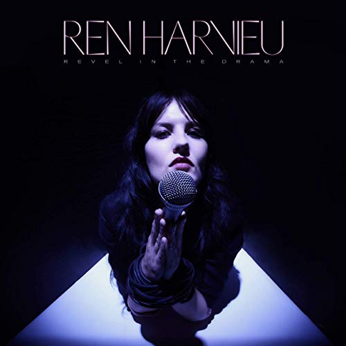 "Album cover featuring a woman holding a microphone, lit from below, against a dark background."