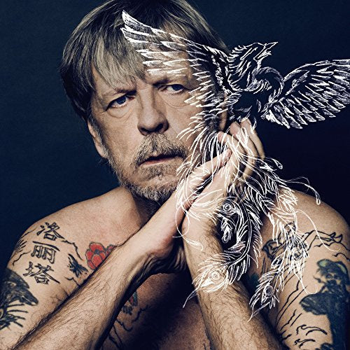Man with tattoos holds a white, sketch-like bird against a dark background.