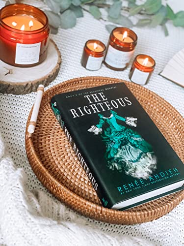 Book "The Righteous" rests on a woven tray with lit candles nearby.
