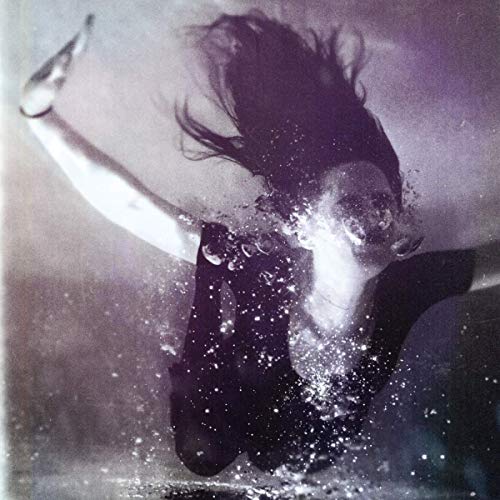 The image depicts a woman emerging from water, with her hair flowing and arms outstretched.