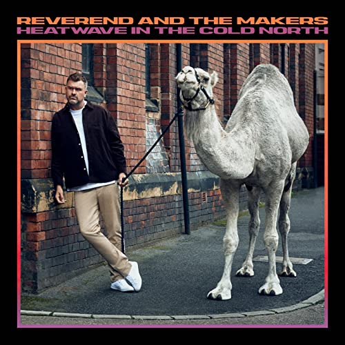 Man with a camel standing in front of a brick building.