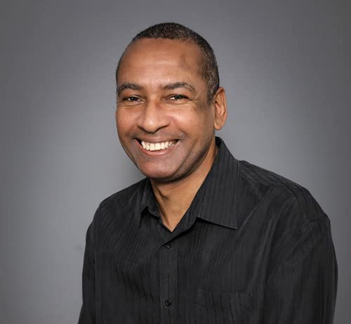 Headshot of a smiling Black man in a black button-down shirt.