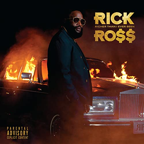 Rick Ross wearing sunglasses stands before a luxury car engulfed in flames.