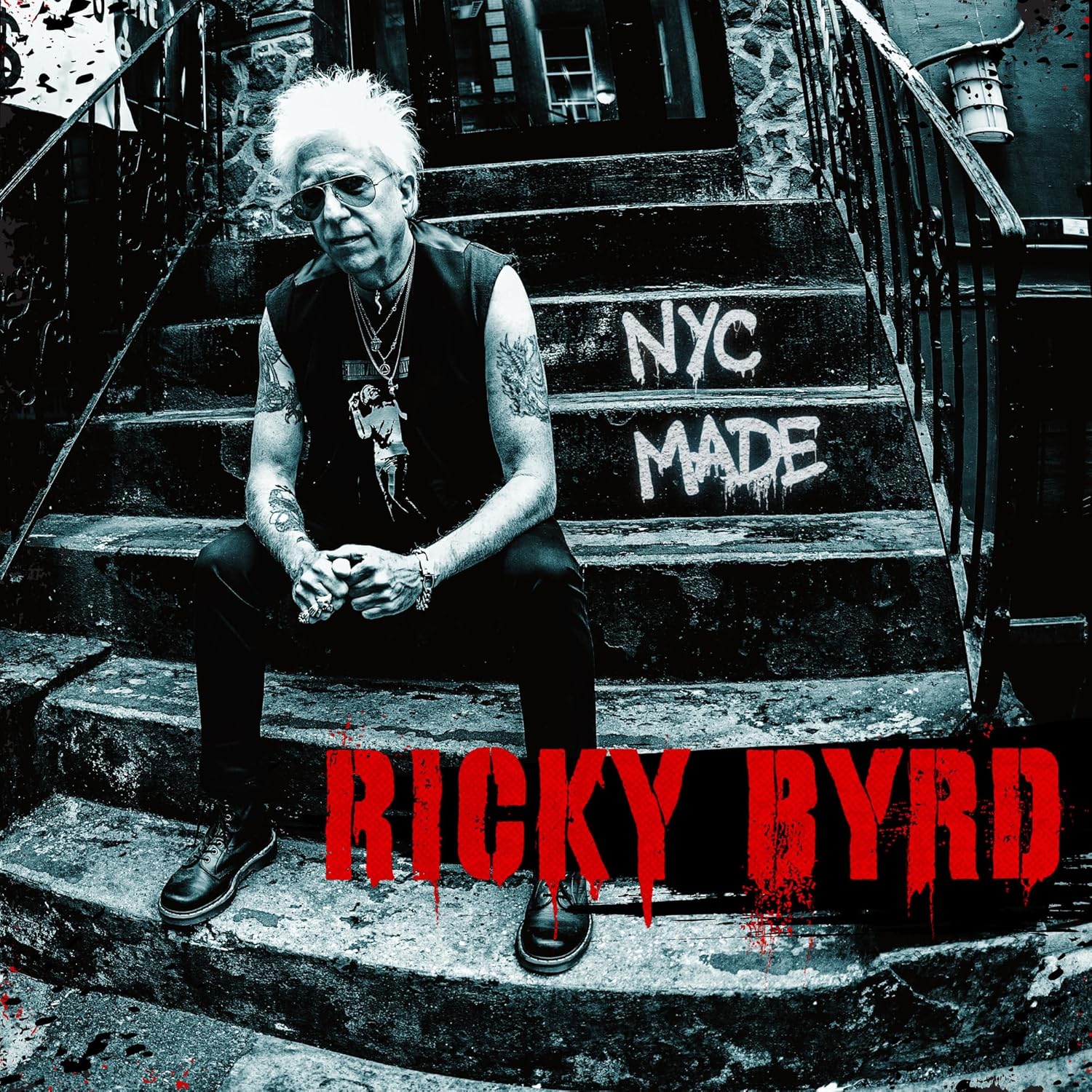 Ricky Byrd sitting on stone steps with NYC MADE written on the stairs.