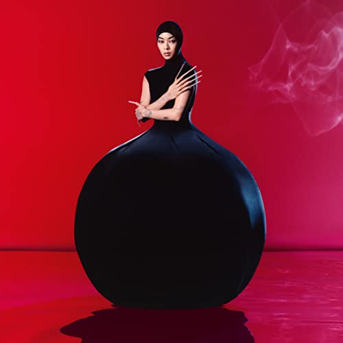 Rina Sawayama in a black gown against a red background.