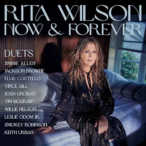 Rita Wilson sits on a bed in a sequined dress on this album cover.