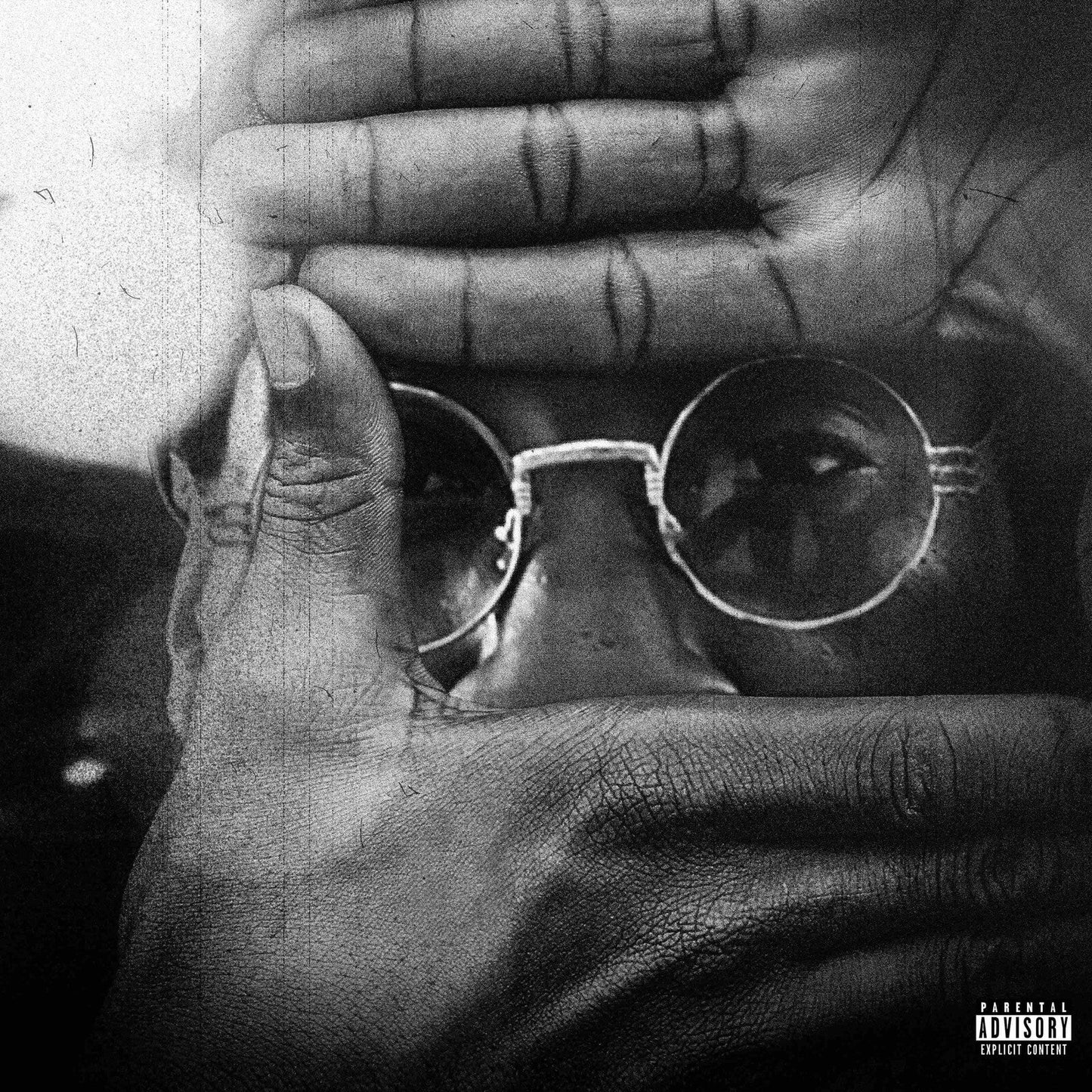 Black and white portrait of a person viewed through hands framing their face.