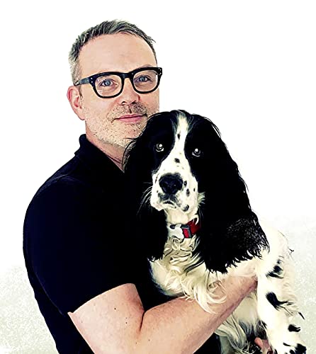 Man in glasses holding a black and white spotted dog.