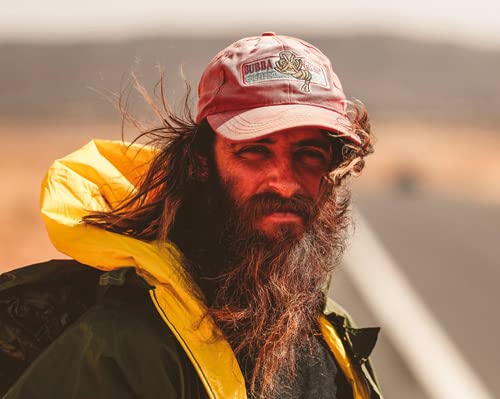 Man with long beard and hair, wearing a cap and jacket.