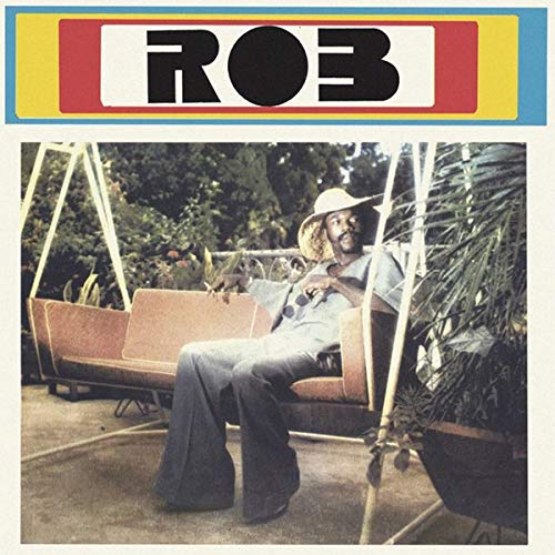 "Album cover with a man sitting on a swing, surrounded by plants."
