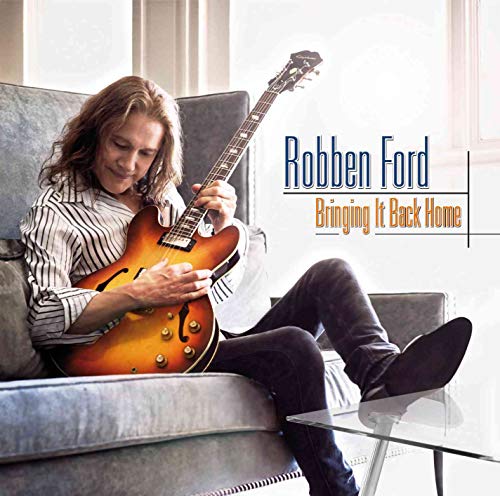 Robben Ford sits with a guitar on a gray couch, album cover.