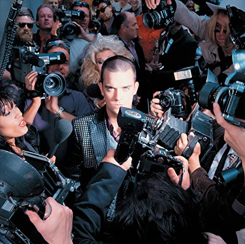 Robbie Williams surrounded by cameras and a crowd of people.