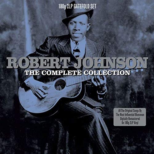 Robert Johnson wearing a hat and suit while playing an acoustic guitar.