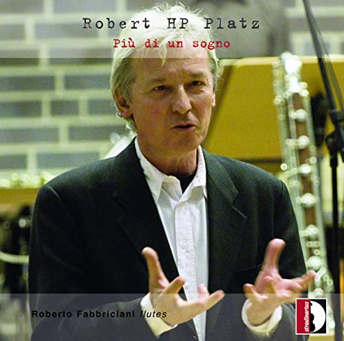Man in a suit gesturing, surrounded by musical instruments, on a CD cover.