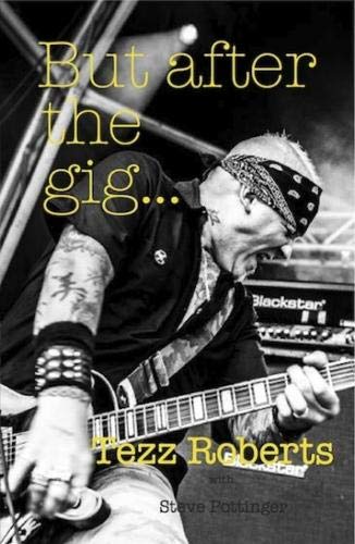 Black and white photo of a tattooed guitarist wearing a bandana playing on stage.
