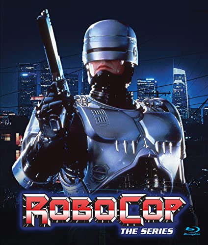 Robocop in silver armor holds a gun with a cityscape behind him at night.